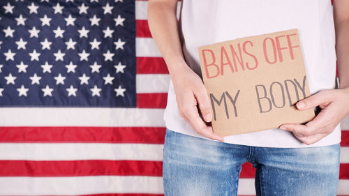 Midsection of woman holding american flag