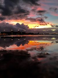 Scenic view of lake against dramatic sky during sunset