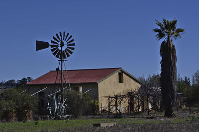 Traditional windmill by tree and building against sky