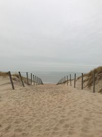 Wooden posts on beach against sky