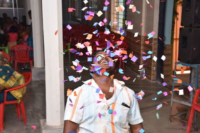 Smiling young man looking at confetti in mid-air