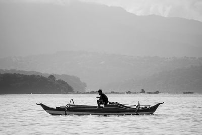 A man on boat sailing on sea against sky