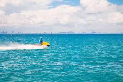 Man riding motorboard on sea against cloudy sky