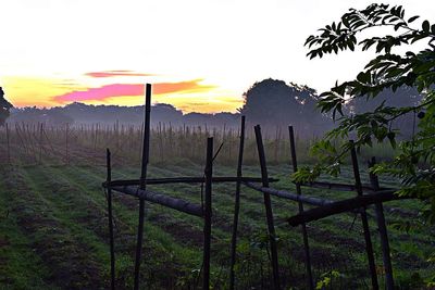 Wooden fence on field against sky during sunset