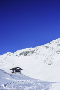 Scenic view of snow covered mountains against clear blue sky