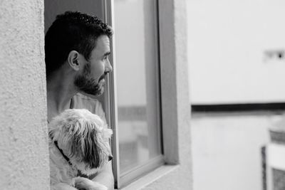 Man with dog looking through window