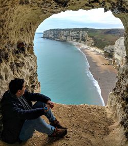 Man sitting on rock by sea