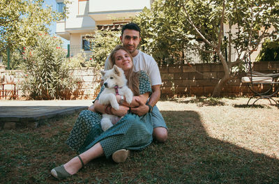 Young couple sitting in the yard with samoyed dog in their hands. family concept.