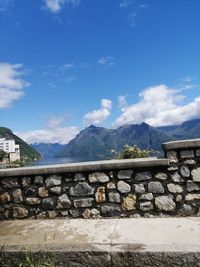 Stack of wooden wall and mountains against blue sky