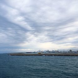 Boats in sea against cloudy sky