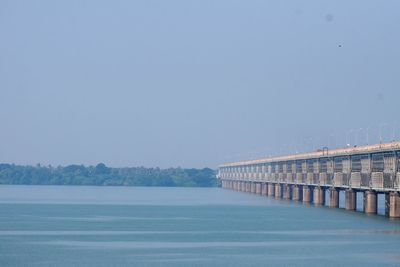 Bridge over sea against clear blue sky