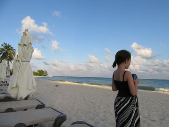 Girl standing at beach against sky
