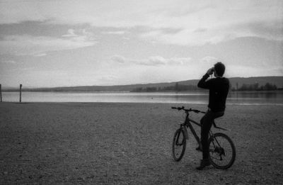 Woman riding bicycle on water against sky