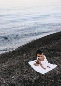 A couple in love spend the night at the sea, kissing and hugging on the beach covered with a blanket