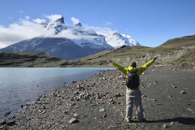 Rear view of man with arms outstretched standing on land