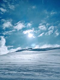 Scenic view of sea by snowcapped mountain against sky