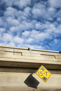 Low angle view of sign on bridge against sky