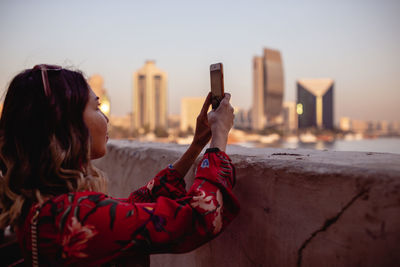 Woman photographing with smart phone in city