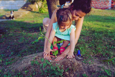 Woman planting with daughter on land