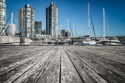Sailboats on pier by buildings against sky in city