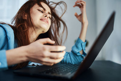 Young woman using mobile phone while sitting on table