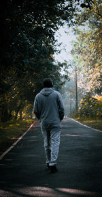 Rear view of man walking on road