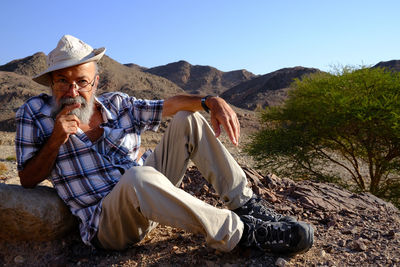 Senior man sitting on mountain in the desert 