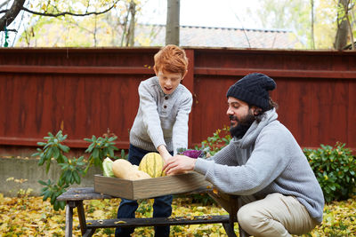 Man and boy arranging vegetable in basket at back yard