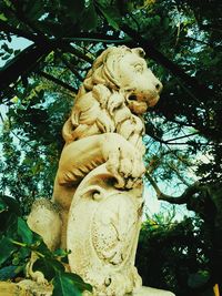 Low angle view of angel statue against trees