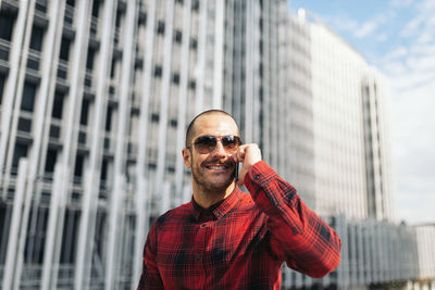 Portrait of smiling man standing against modern building