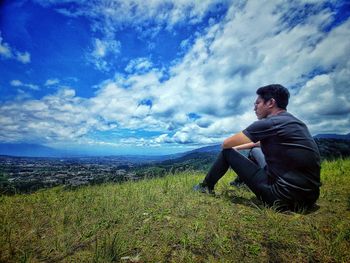 Side view of man looking at sea against sky