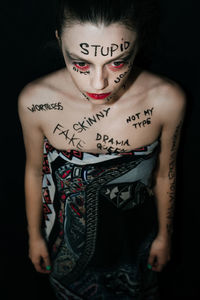 High angle view of serious woman with text on body against black background