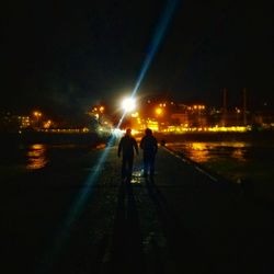 People walking on illuminated city at night
