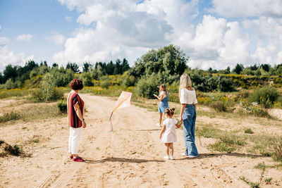 A charming little girl and her family are flying a kite. family, generation, time together