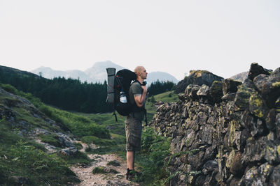 Man standing on rock against sky