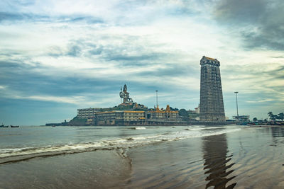 View of building by sea against cloudy sky