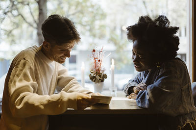 Boyfriend and girlfriend reading menu card while sitting at bar