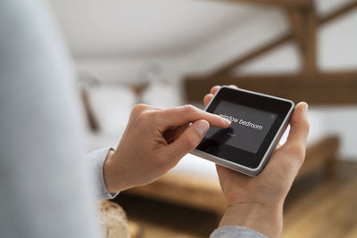 Mid adult woman using smart home device at home