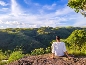 Isolated man sitting at mountain top with bright blue sky at morning from flat angle 