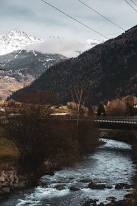 Scenic view of river by mountains against sky during winter