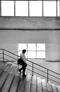 Rear view of man walking on railing against wall