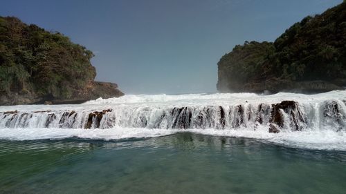 Scenic view of waterfall against sky