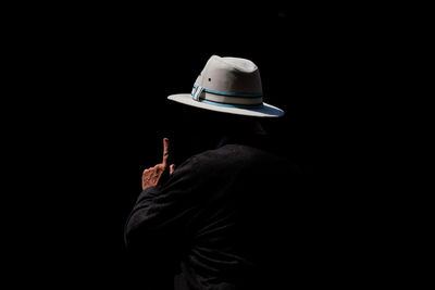 Rear view of person wearing hat against black background