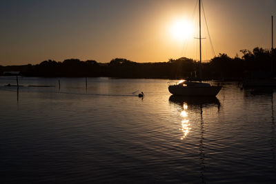 Silhouette sailboats in lake against sky during sunset