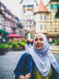 Woman in hijab looking up in city