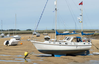 Sailboats moored at harbor against clear sky