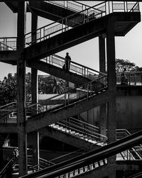 Woman on staircase of building against sky