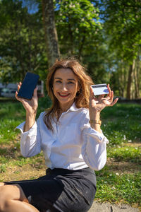 Young woman using mobile phone while sitting on field