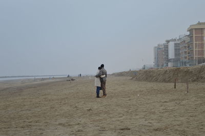 Rear view of man walking on beach against clear sky