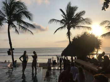 People at beach against sky during sunset